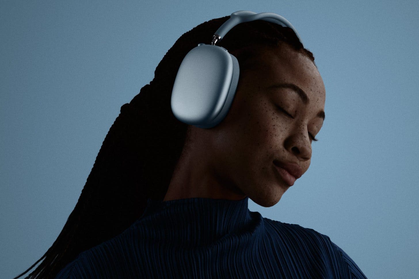 an image of a woman with her eyes shut, wearing a pair of silver AirPods Max 2