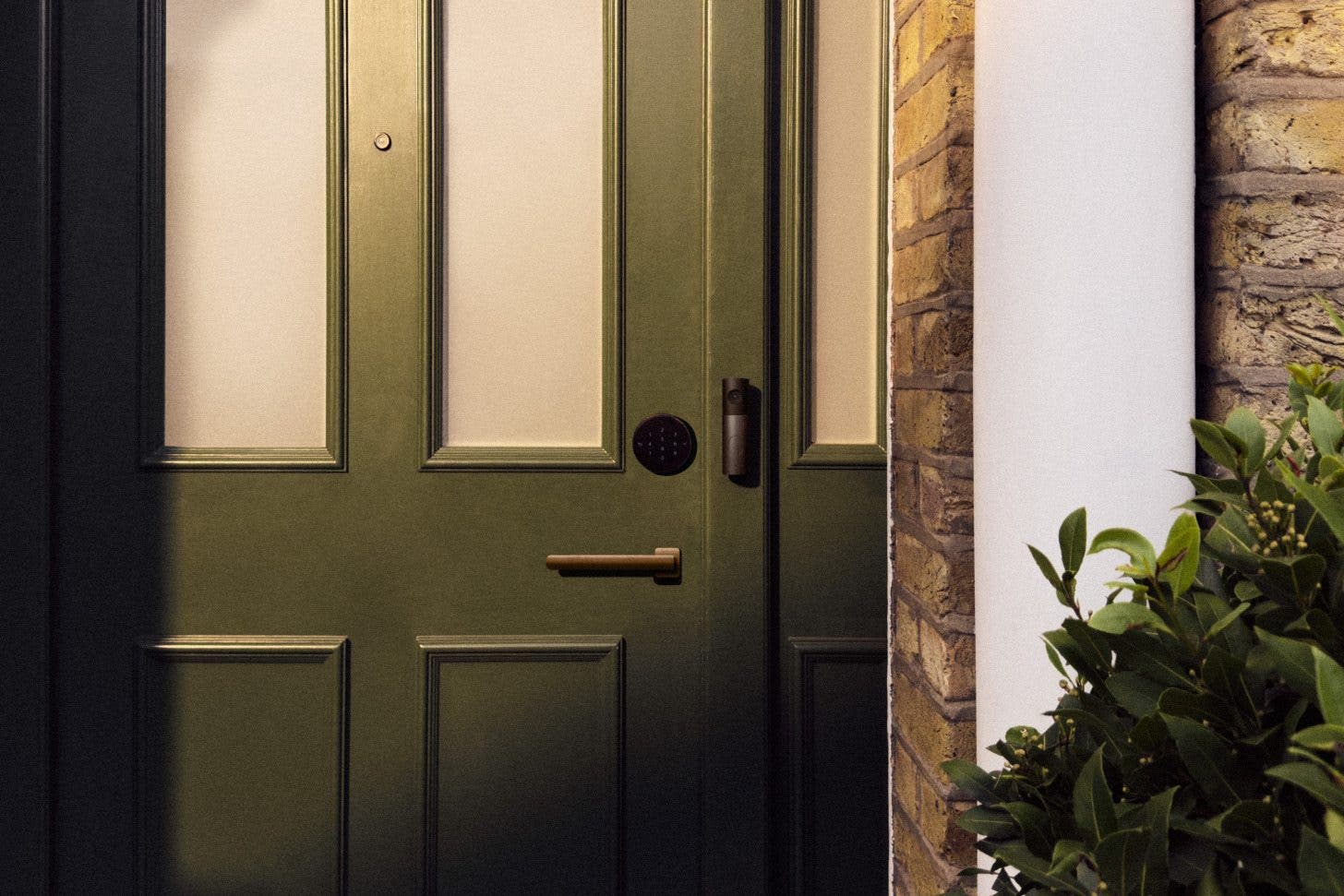 an image of the front door of a house with an LG smart lock above the door handle and an LG video doorbell mounted alongside it