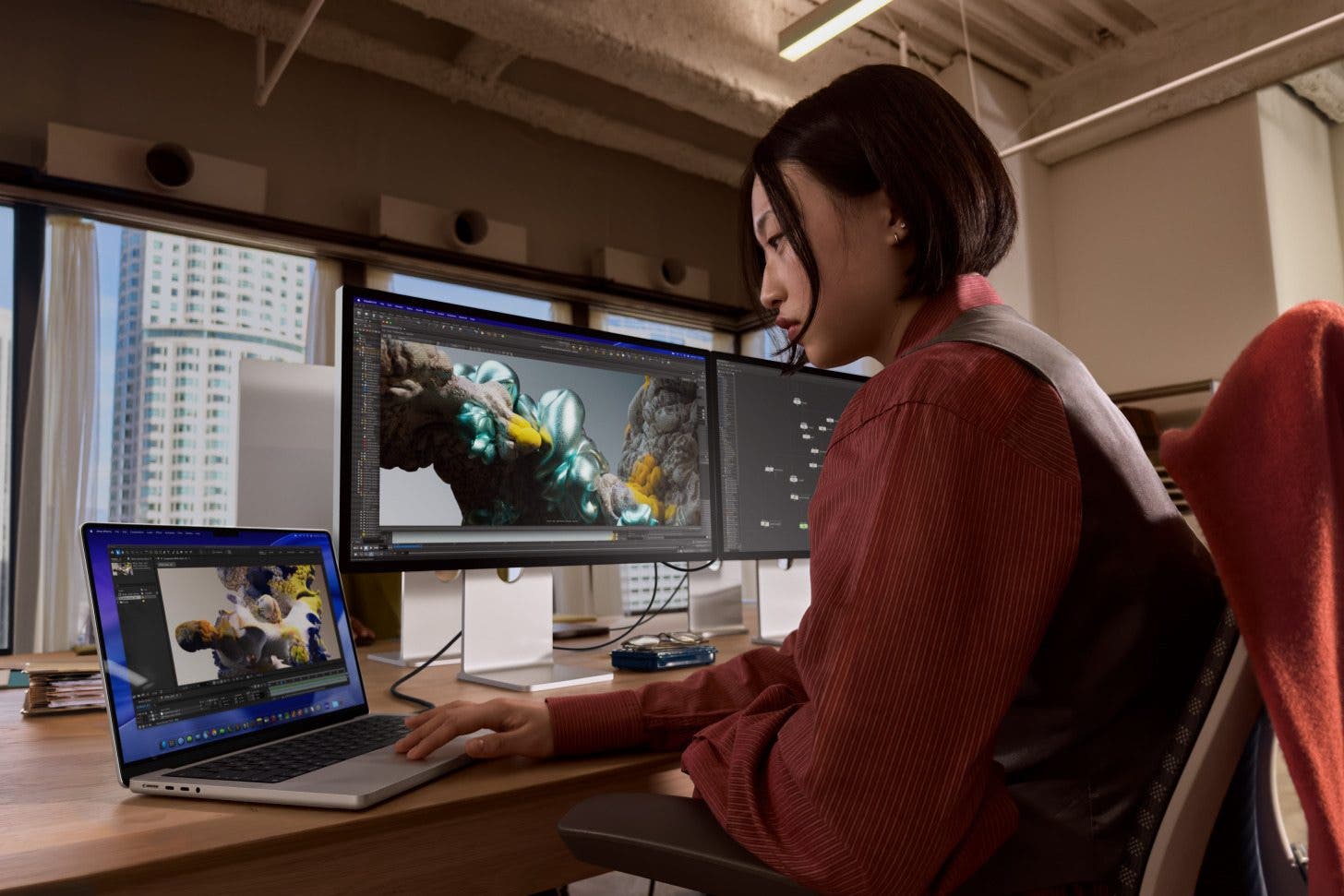 a photo of a woman using a macbook pro connected to two external display