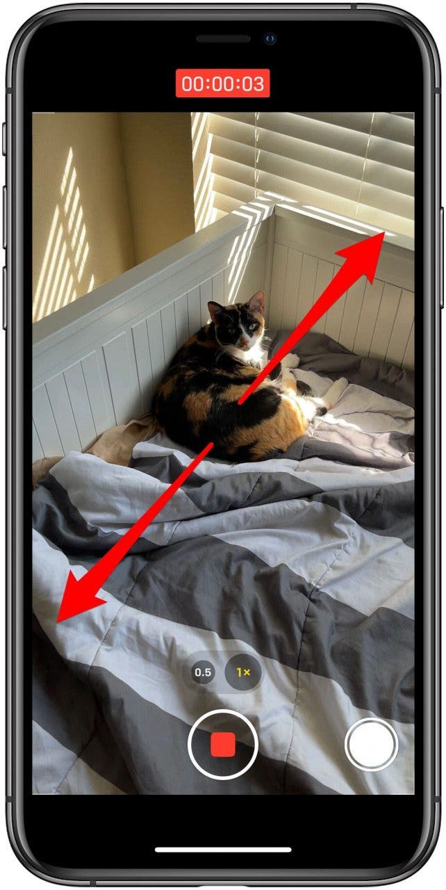 Camera app in Video mode, while recording, with markings showing a zoom gesture.
